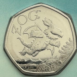 Peut inclure: Une pièce de monnaie argentée avec un motif de dragon. La pièce porte l'inscription "OG" et "50". Le dragon est représenté avec des ailes, sur un paysage d'arbres et de montagnes.