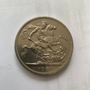 Può includere: Una moneta d'argento con la raffigurazione di un cavaliere a cavallo che uccide un drago. La moneta ha l'anno 1951 inciso sul fondo.