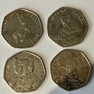 以下が含まれることがあります： ピーターラビットの物語のキャラクターが描かれた銀色のコイン4枚。コインには、ピーターラビット、ジェレミー・フィッシャー氏、トム・キトゥン、ベンジャミン・バニーが描かれています。