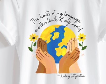 Può includere: Maglietta bianca con una grafica di mani che tengono un globo con la citazione "I limiti del mio linguaggio sono i limiti del mio mondo." di Ludwig Wittgenstein.
