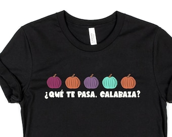 Puede incluir: Camiseta negra con una fila de cinco calabazas de colores y el texto "¿Qué te pasa, calabaza?" en blanco.