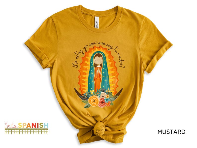 Puede incluir: Camiseta amarilla mostaza con un gr&aacute;fico de la Virgen Mar&iacute;a con una t&uacute;nica azul y dorada. El texto "No estoy yo aqu&iacute; que soy tu madre?" est&aacute; impreso en la camiseta.