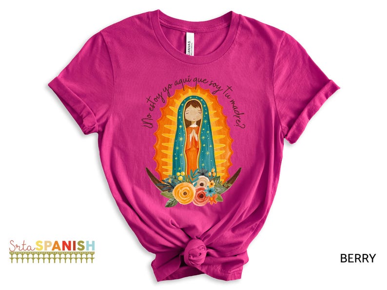Puede incluir: Una camiseta rosa con un gr&aacute;fico de la Virgen Mar&iacute;a en un marco dorado. El texto "No estoy yo aqu&iacute; que soy tu madre?" est&aacute; impreso en la camiseta.