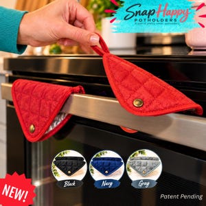 May include: Two red quilted triangular potholders with a metallic snap button closure. One potholder hangs from an oven handle, while the other is held up. Additional color options shown include black, navy, and gray fabric versions.