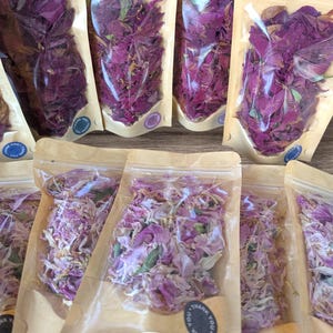 May include: Multiple clear, resealable pouches filled with dried flower petals. The top row contains deep magenta petals, while the bottom row features lighter pink and white petals. Each pouch has a small circular sticker that says Thank You.