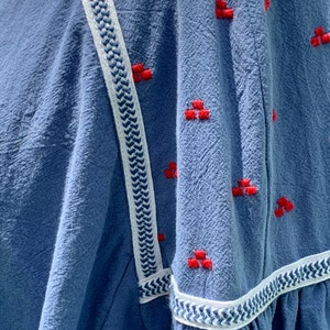 May include: A blue cotton shirt with white and blue trim and red embroidered details.