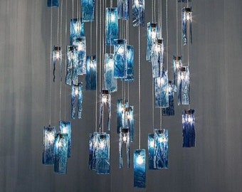 May include: A modern chandelier with multiple blue glass rectangular pendants hanging from a circular metal frame.