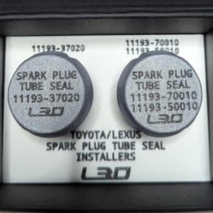 May include: Two gray spark plug tube seals with the text "SPARK PLUG TUBE SEAL" and part numbers. The seals are in a black box with the text "TOYOTA/LEXUS SPARK PLUG TUBE SEAL INSTALLERS" and the L3D logo.