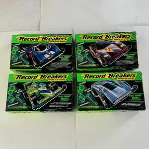 May include: Four boxed toy cars from the "Record Breakers" series. Each box features a different car design in vibrant colors like blue, green, and black. The boxes have text that reads "Customize" and "Dual-Turbo Series".