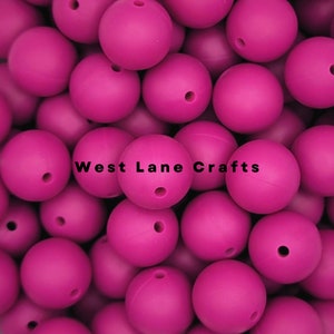 May include: A large pile of bright pink silicone beads. The beads are smooth and round, with a small hole in the center of each bead.  West Lane Crafts.
