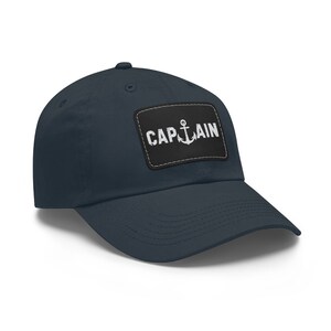 May include: A navy blue baseball cap with a black patch that says "CAPTAIN" with a white anchor symbol.