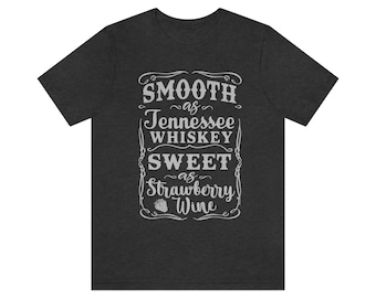 Può includere: T-shirt grigio scuro melange con una grafica in stile vintage che recita "Smooth as Tennessee Whiskey Sweet as Strawberry Wine".