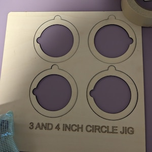 May include: A wooden jig with four cutouts for creating circles. The jig has two 3-inch circles and two 4-inch circles. The text "3 AND 4 INCH CIRCLE JIG" is printed on the jig.