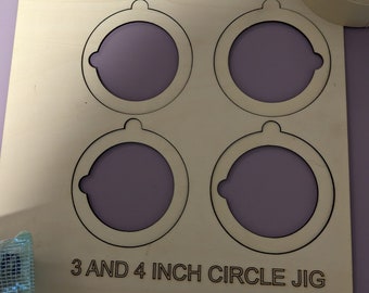 Op de afbeelding: Een houten jig met vier uitsparingen voor het maken van cirkels. De jig heeft twee cirkels van 7,6 cm en twee cirkels van 10,2 cm. De tekst "3 AND 4 INCH CIRCLE JIG" is op de jig gedrukt.