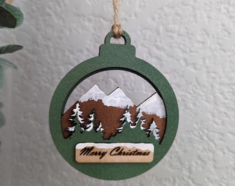 Wooden layered ornament with hand painted trees and mountains