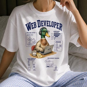 Könnte beinhalten: Ein weißes T-Shirt mit einer Grafik einer Stockente, die Kopfhörer und eine Brille trägt und an einem Laptop arbeitet. Das Design enthält Textbeschriftungen wie Web Developer, The Dev Cycle, Language Fluency, Debugging Techniques und Stack Overflow Survival Kit sowie verschiedene Symbole und Diagramme.