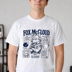 Może przedstawiać: Biały t-shirt z krótkim rękawem z ciemnoniebieskim nadrukiem graficznym przedstawiającym postać Foxa McClouda ze skrzyżowanymi ramionami. Wzór zawiera tekst, wykres kołowy, wykres liniowy oraz listę codziennych zadań na klatce piersiowej.