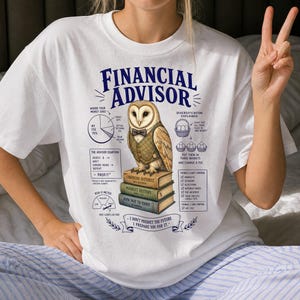 May include: A white t-shirt featuring a graphic of a barn owl wearing a vest and bowtie, perched on a stack of books. The design includes text reading FINANCIAL ADVISOR, charts, and financial diagrams with labels like THE ADVISOR EQUATION.