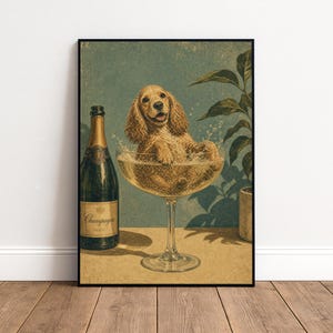 May include: A framed wall art print featuring a golden-brown spaniel sitting inside a large, wide-rimmed champagne coupe glass. Next to the glass stands a dark green bottle with a label reading Champagne. The background is a muted teal color.