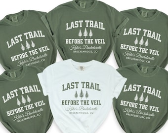 May include: Six green t-shirts with white text that reads "Last Trail Before The Veil" and "Katie's Bachelorette Breckenridge, CO". One white t-shirt with the same text.