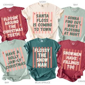 K&ouml;nnte beinhalten: Sechs kurz&auml;rmelige T-Shirts in Karmesinrot, Elfenbein und Beere. Jedes Shirt zeigt einen vertikalen Streifenhintergrund mit Sternakzenten und weihnachtlichen Texten wie Flossin Around The Christmas Teeth, Santa Floss Is Coming To Town und weiteren.