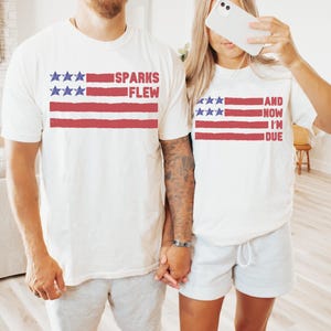 May include: A couple wearing white t-shirts with an American flag design and text that reads "Sparks Flew" and "And Now I'm Due".