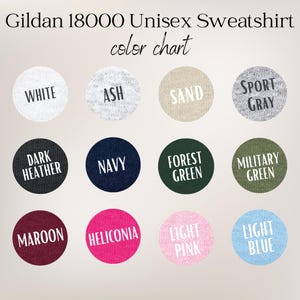K&ouml;nnte beinhalten: Eine Gildan 18000 Unisex-Sweatshirt-Farbkarte mit zw&ouml;lf kreisf&ouml;rmigen Stoffmustern, beschriftet mit White, Ash, Sand, Sport Gray, Dark Heather, Navy, Forest Green, Military Green, Maroon, Heliconia, Light Pink und Light Blue.