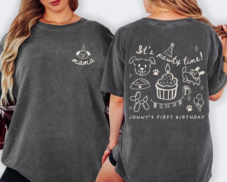 May include: Dark gray t-shirt with a crew neck. The front features a small white illustration of a dog wearing a party hat and the word "mama". The back of the shirt has the text "It's pawty time!" with dog-themed illustrations and "Jonny's First Birthday".