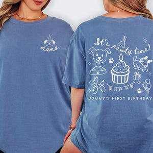 May include: Blue long-sleeve shirt with white graphic designs. The front features a dog illustration and the word "mama". The back has the text "It's pawty time!" with dog-themed illustrations and "Jonny's First Birthday".