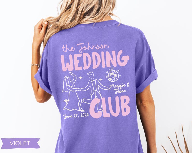 May include: Violet-colored t-shirt with the text "the Johnson WEDDING CLUB" in pink. The design includes a dancing couple, a disco ball, and the date "June 27, 2026." The shirt is a casual style.