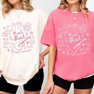 May include: Two t-shirts with a pink graphic design featuring a guitar, cowboy hat, and the text "Nash Bash" and "Taylor's Bachelorette". The t-shirt on the left is ivory and the t-shirt on the right is pink.
