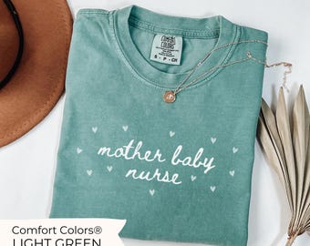 Op de afbeelding: Een lichtgroen T-shirt met de tekst "mother baby nurse" in witte letters en kleine witte hartjes die rond de tekst zijn verspreid. Het shirt is gemaakt door Comfort Colors.