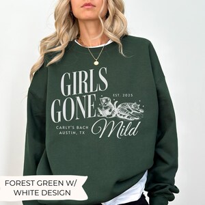 May include: Forest green sweatshirt with a white design that says "Girls Gone Mild" with a cat illustration and the text "Carly's Bach Austin, TX Est. 2025".