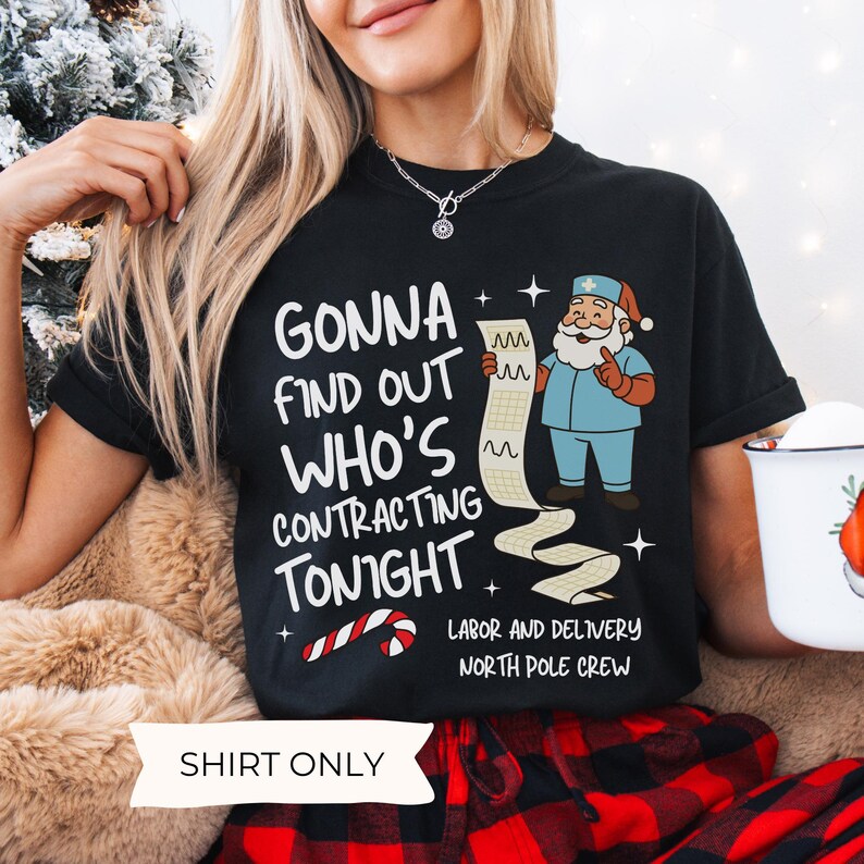 Puede incluir: Camiseta negra con el texto "GONNA FIND OUT WHO'S CONTRACTING TONIGHT" y un Pap&aacute; Noel de dibujos animados con uniforme m&eacute;dico. La camiseta tambi&eacute;n presenta un bast&oacute;n de caramelo y las palabras "LABOR AND DELIVERY NORTH POLE CREW".