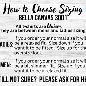 Op de afbeelding: Een wit houten bord met zwarte tekst die uitlegt hoe je de juiste maat kunt kiezen voor Bella Canvas 3001 T-shirts. De tekst legt uit dat de shirts unisex zijn en passen tussen mannen- en vrouwenmaten. Het bord geeft ook maatadvies voor zowel dames als heren.