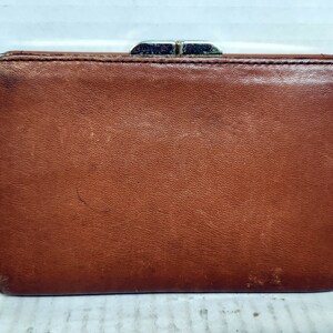 May include: A brown leather wallet with a silver clasp.