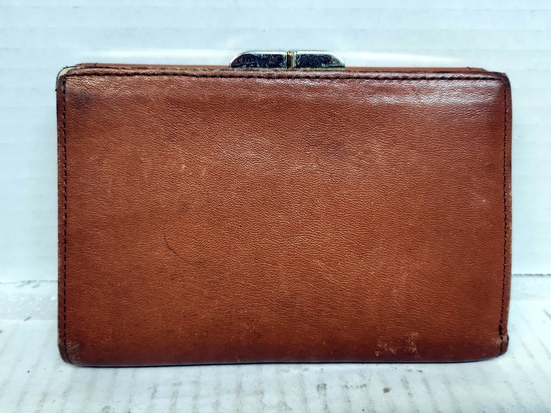 May include: A brown leather wallet with a silver clasp.