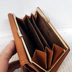 May include: A brown leather wallet with a gold metal clasp. The wallet has multiple compartments and is folded closed.
