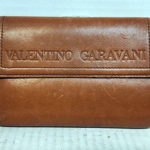 May include: A brown leather wallet with the embossed text "VALENTINO GARAVANI".