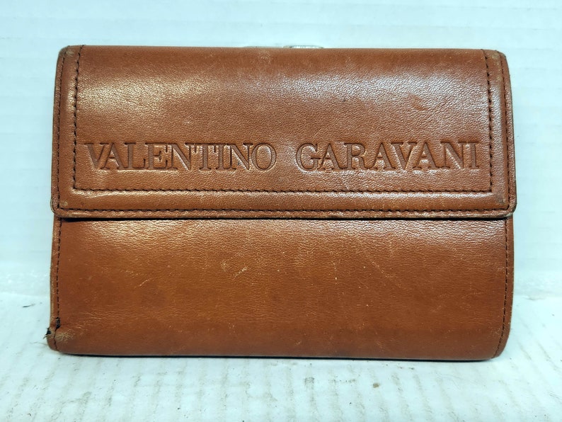 May include: A brown leather wallet with the embossed text "VALENTINO GARAVANI".