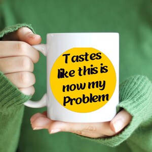 May include: White ceramic mug with a yellow circle and black text that reads "Tastes like this is now my problem".