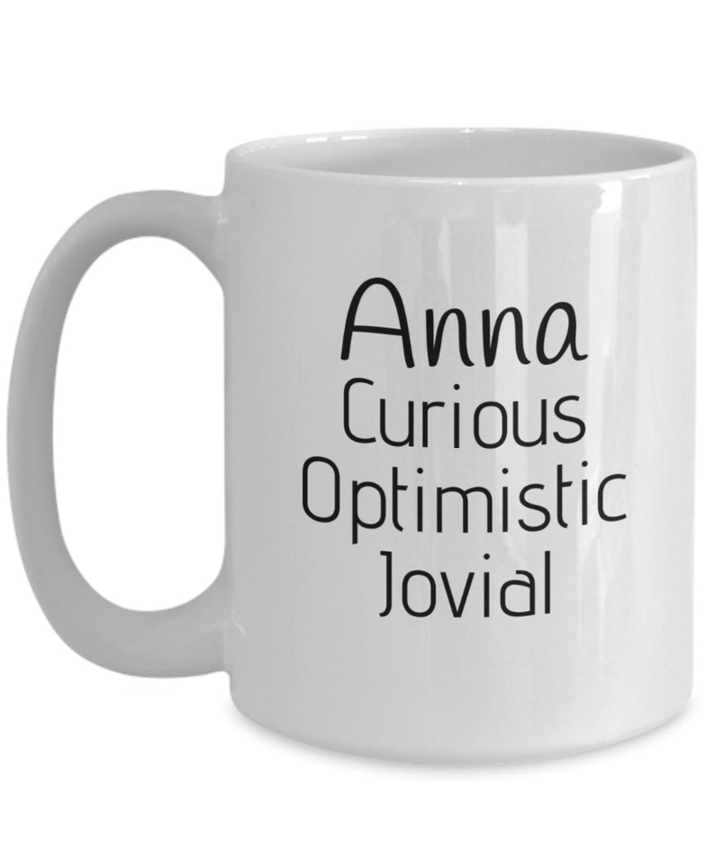 Puede incluir: Taza de caf&eacute; de cer&aacute;mica blanca con una inscripci&oacute;n negra que dice "Anna curiosa optimista jovial".