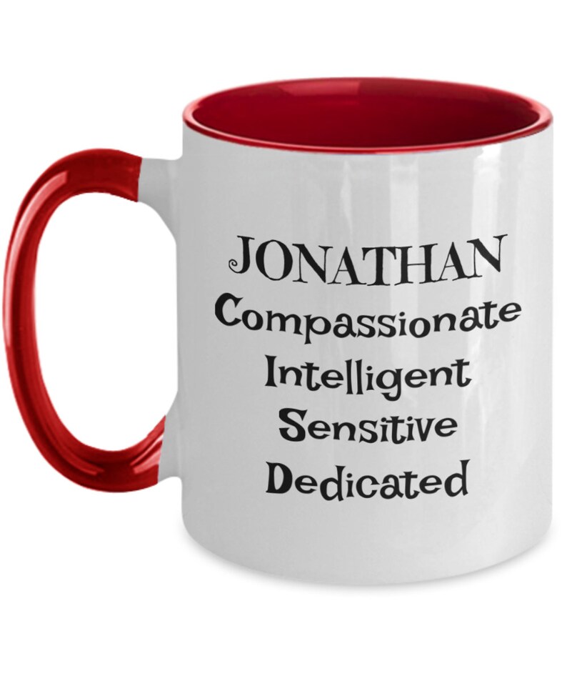 May include: White ceramic coffee mug with a red rim and handle. The mug has black text that reads "JONATHAN Compassionate Intelligent Sensitive Dedicated".