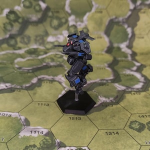 May include: A black and blue miniature mech robot with a red eye, standing on a black hexagonal base. The robot has articulated limbs and a weapon on its side. It is set against a green and tan hexagonal map.