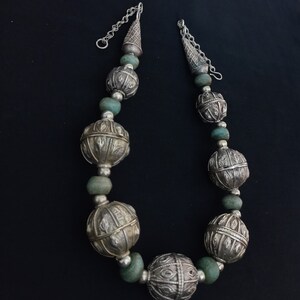 May include: A silver and turquoise beaded necklace with large, ornate silver balls. The necklace has a silver chain closure.