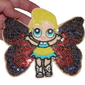 May include: A colorful iron-on patch featuring a cartoon girl with blonde hair and blue eyes wearing a yellow dress and butterfly wings. The wings are made of red, blue, and black sequins.
