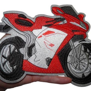 May include: Embroidered patch of a red and white motorcycle with black wheels. The motorcycle is a sportbike with a fairing and a single seat.