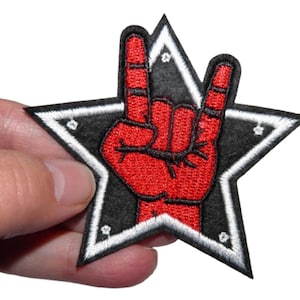 Peut inclure: Patch brodé rouge à repasser représentant une main faisant le geste rock and roll à l'intérieur d'une étoile noire avec un contour blanc.