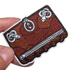 Peut inclure: Un journal relié en cuir marron avec un motif de serpent et une fermeture éclair argentée. Le journal a un fond blanc et est brodé d'un motif de serpent.