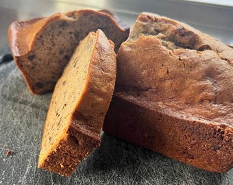 May include: Three slices of banana bread on a gray cutting board. The bread is golden brown and has a slightly crumbly texture.